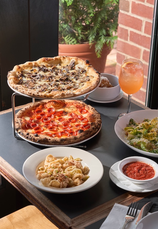 Wood-fired pizzas with arugula and prosciutto and rigatoni in tomato sauce shared family-style at Pizzeria Stella
