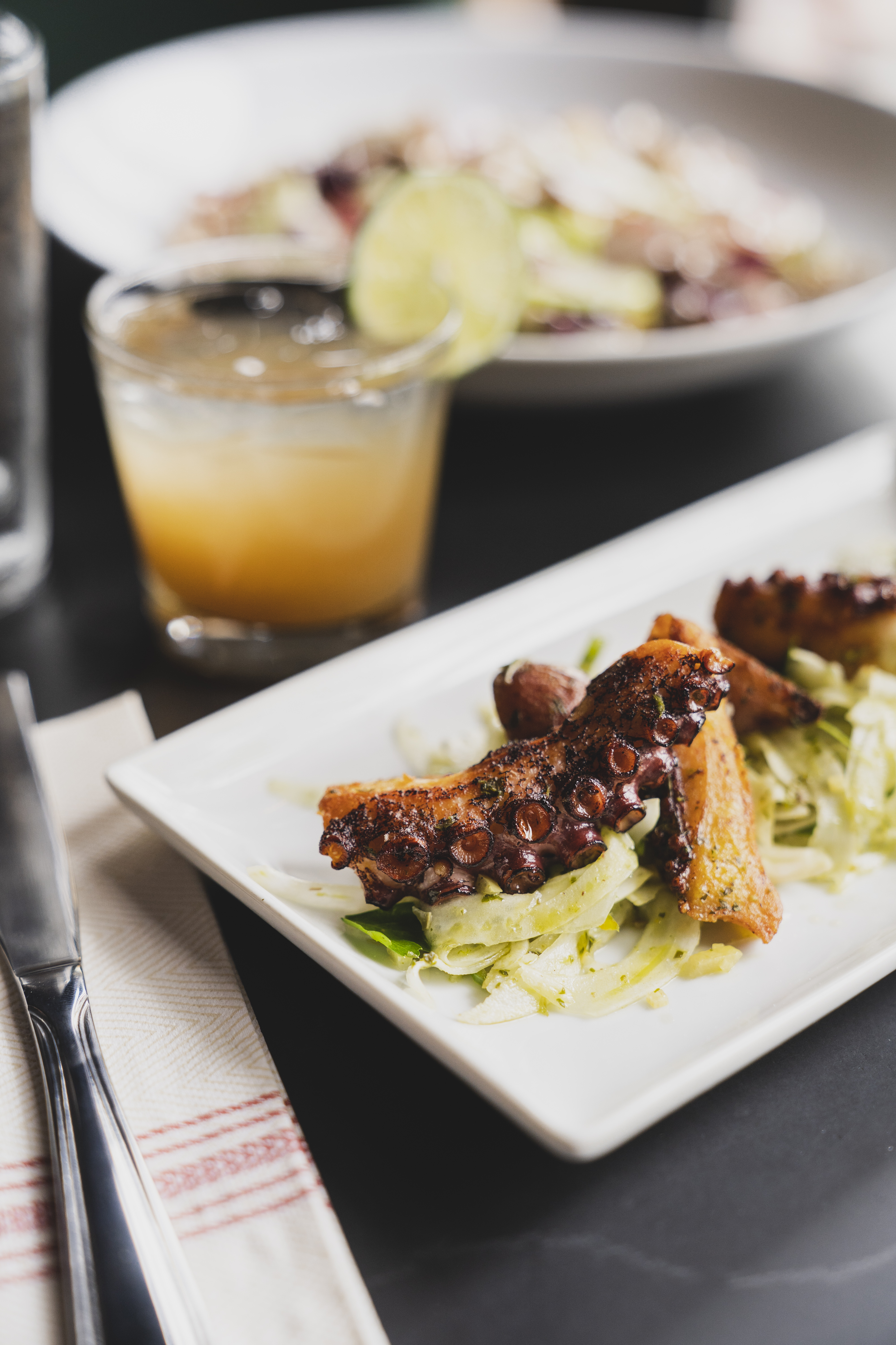 A plate of grilled octopus with a cocktail